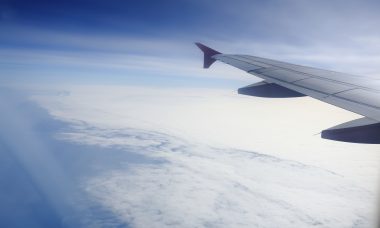 how can we maximise our travel? Wing of an airplane flying above the clouds. people looks at the sky