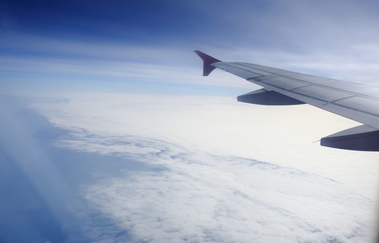 how can we maximise our travel? Wing of an airplane flying above the clouds. people looks at the sky