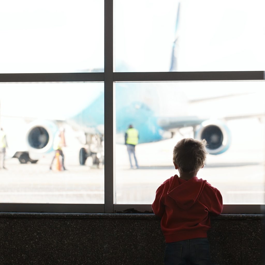 Boy looks at the plane at the airport silhouette shot from back